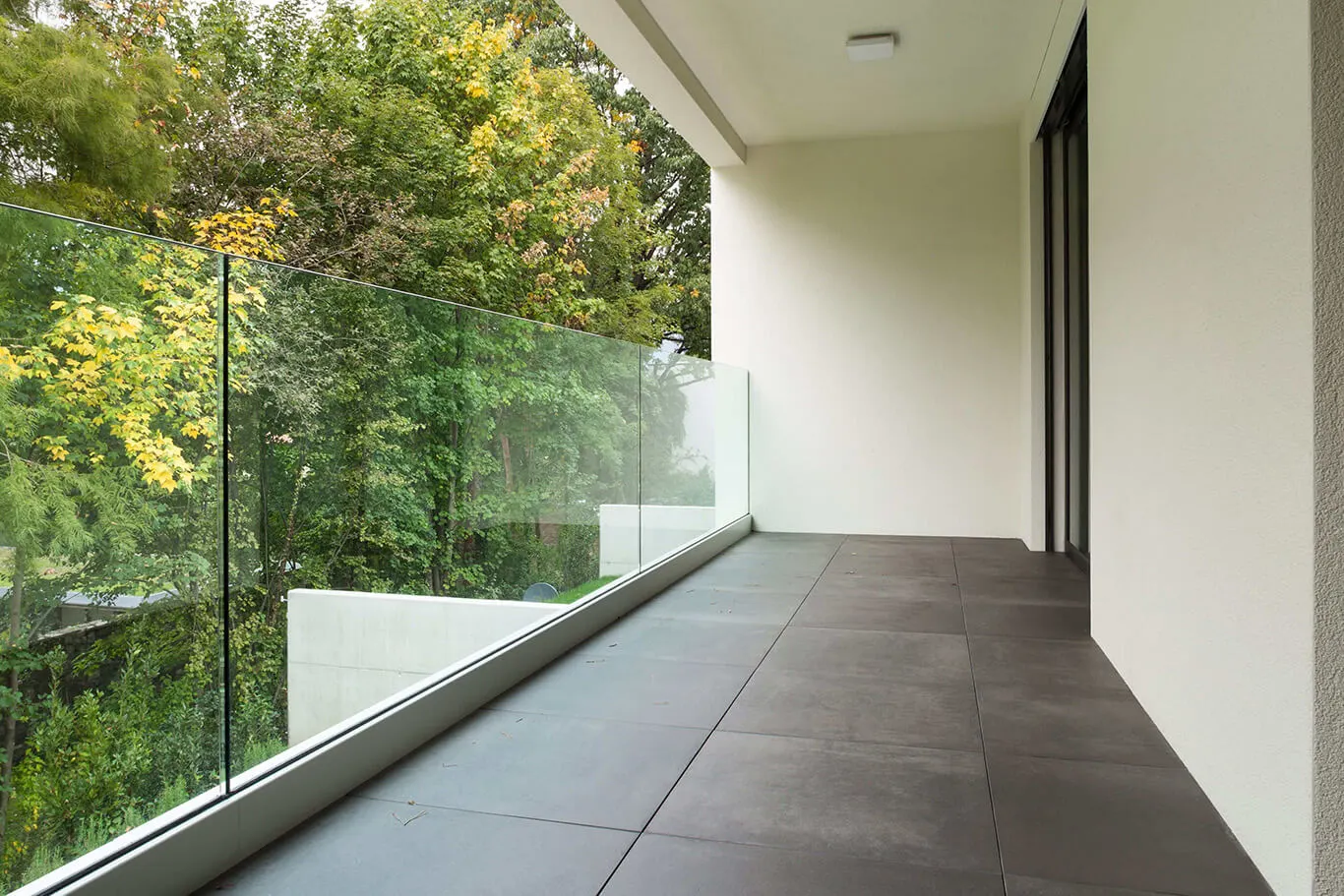 Waterdoorlatend terras donkere tegels met glazen wand